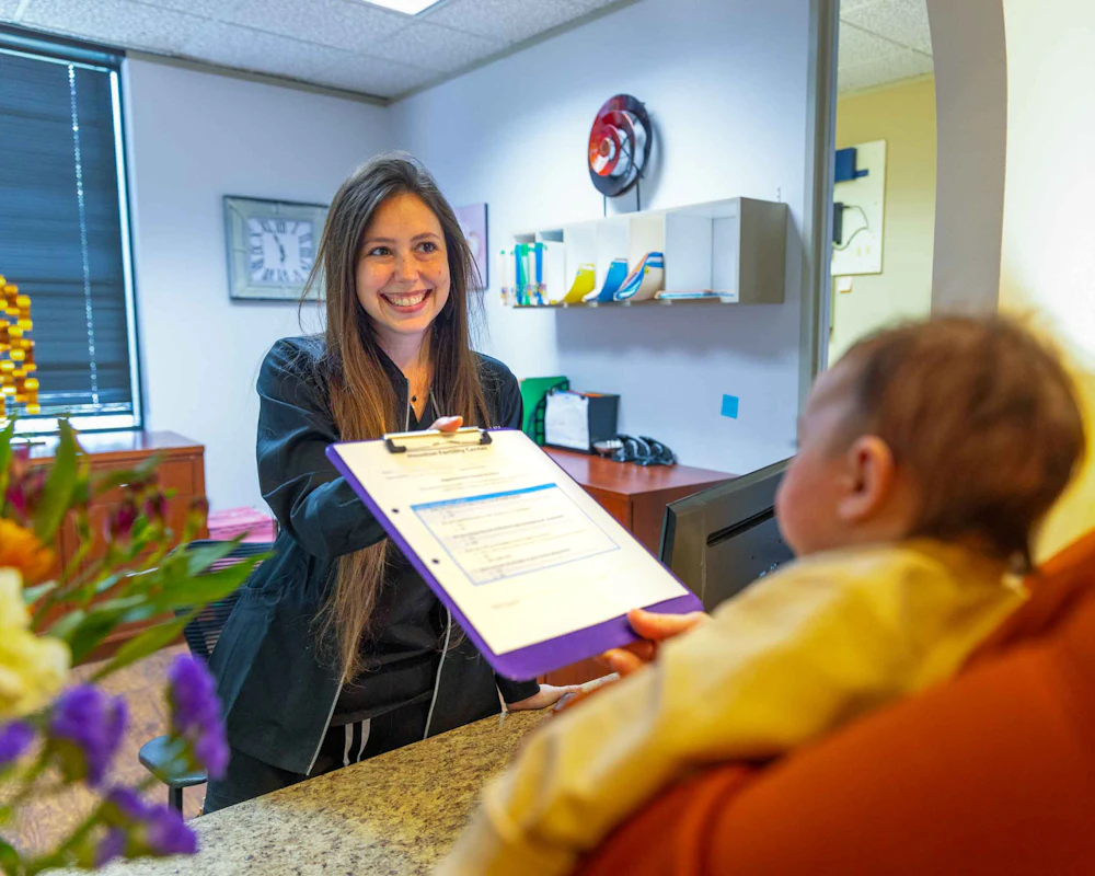Staff handing clipboard to patient