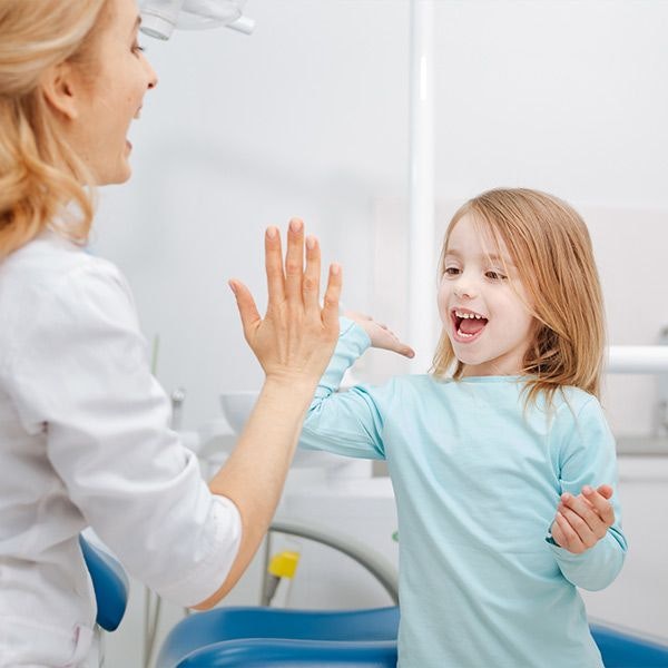 Young girl giving dental hygienist a high five