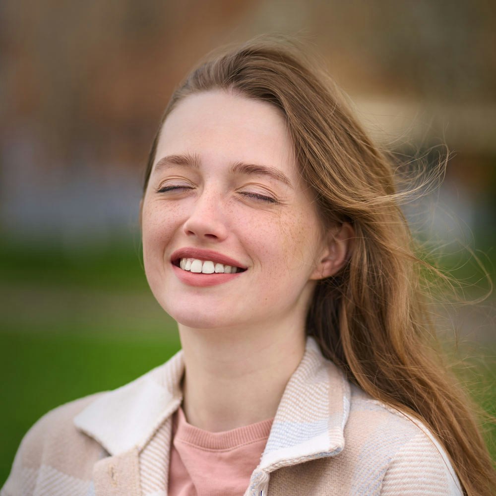 Smiling woman with eyes closed outside