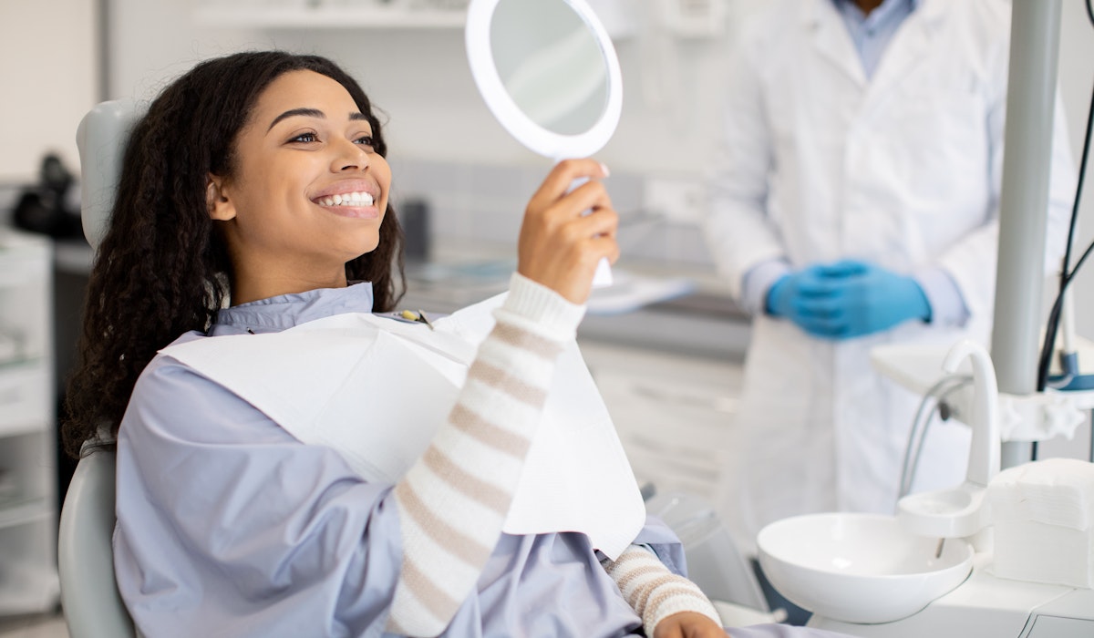 dental patient smiling in a handheld mirror