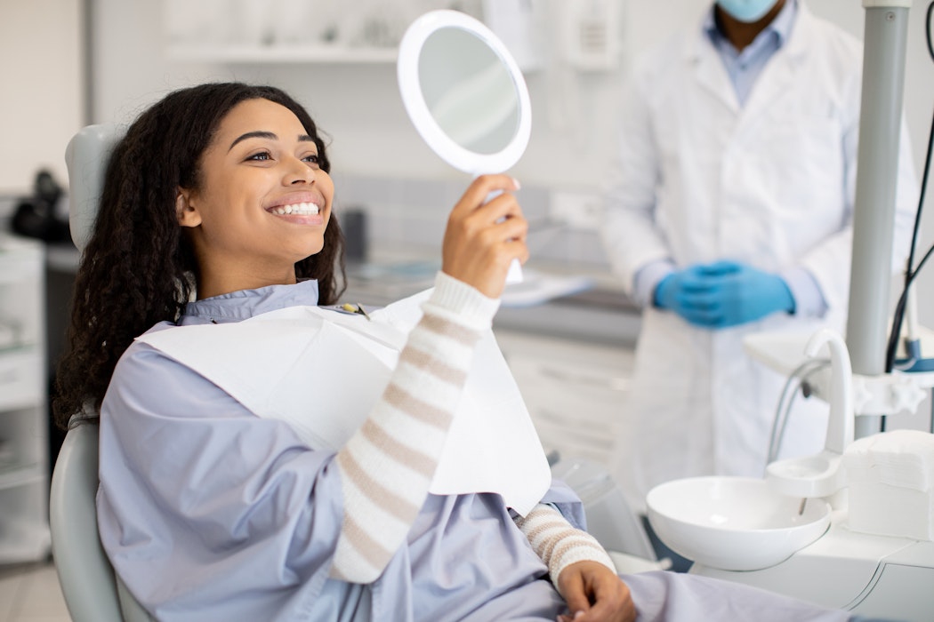 dental patient smiling in a handheld mirror