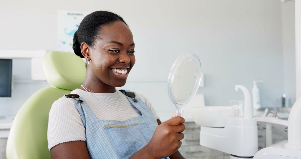 Whitening patient smiling in a hand mirror