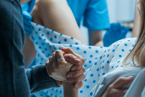 Woman holding man's hand during delivery