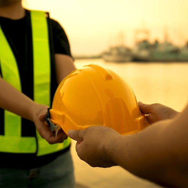 Construction worker being passed a hard hat