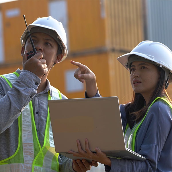Construction workers with laptop and walkie-talkie