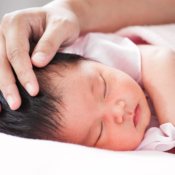 A person's hand cradling a baby's head