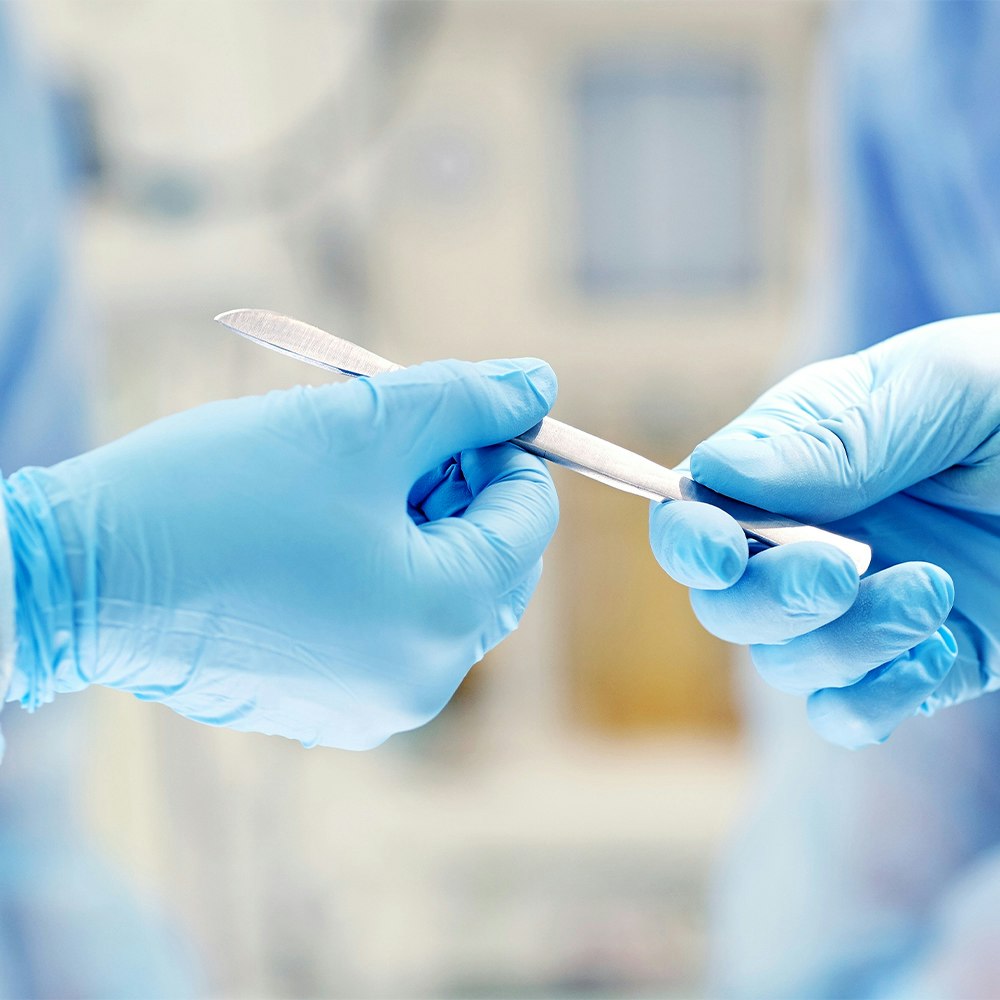 Gloved hands exchanging a scalpel