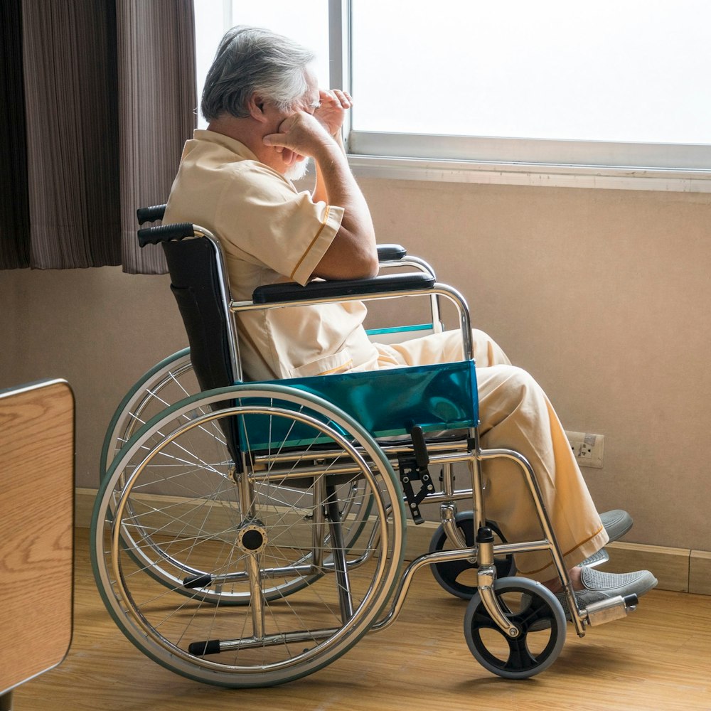 Neglected nursing home resident in a wheelchair sadly looking out the window