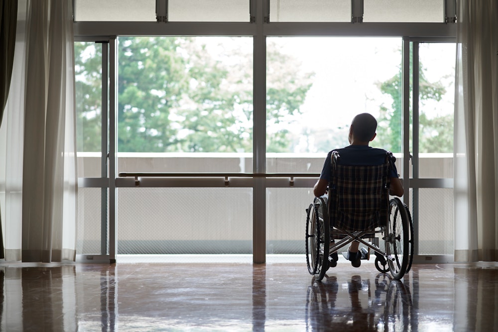 person looking out the window in a wheelchair