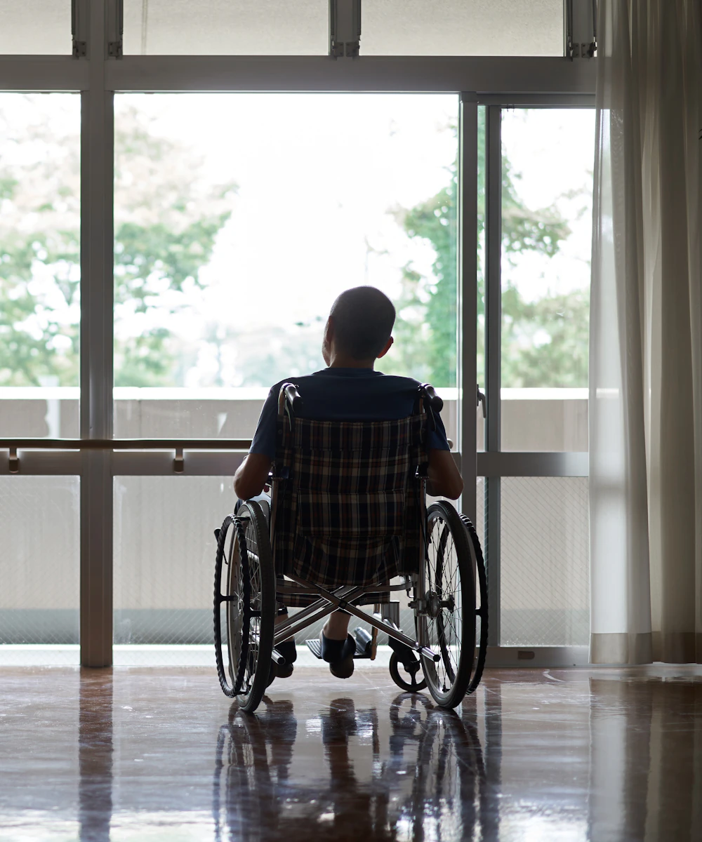 person looking out the window in a wheelchair