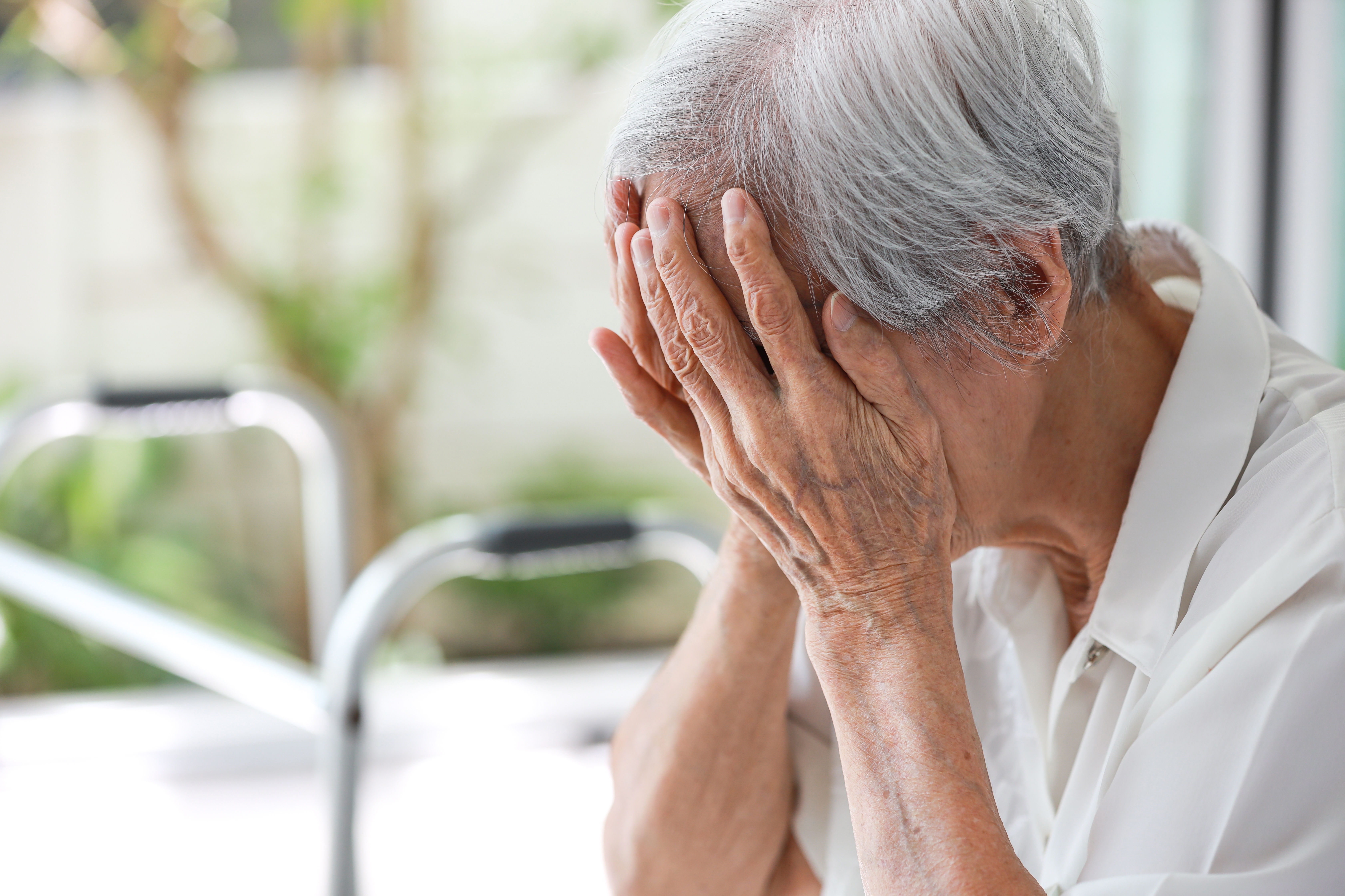 senior woman holding head in hands