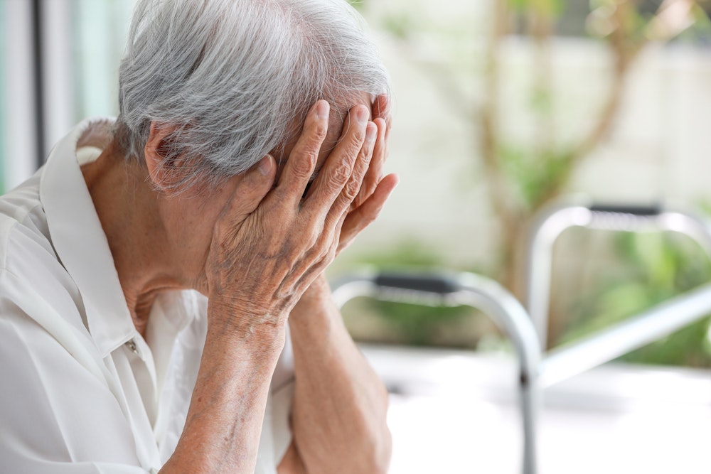 senior woman holding head in hands