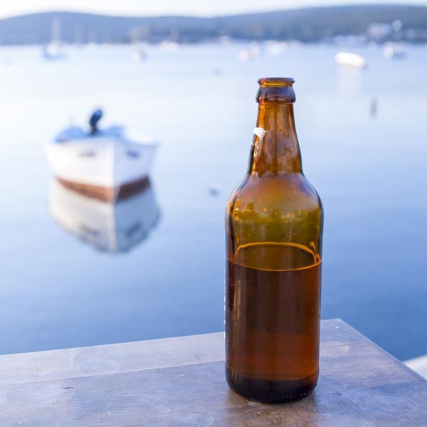 Half Empty Beer Bottle with Boat in Background