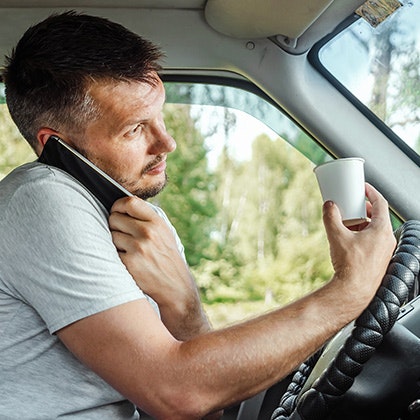 Driver talking on phone while holding a cup