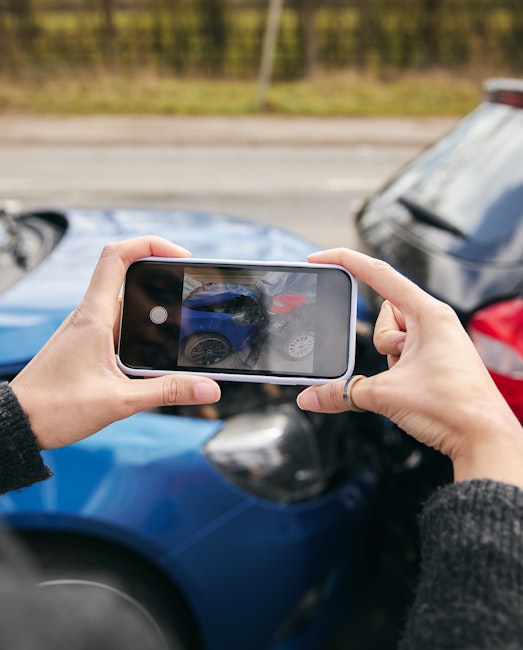 Person taking a photograph of a car wreck