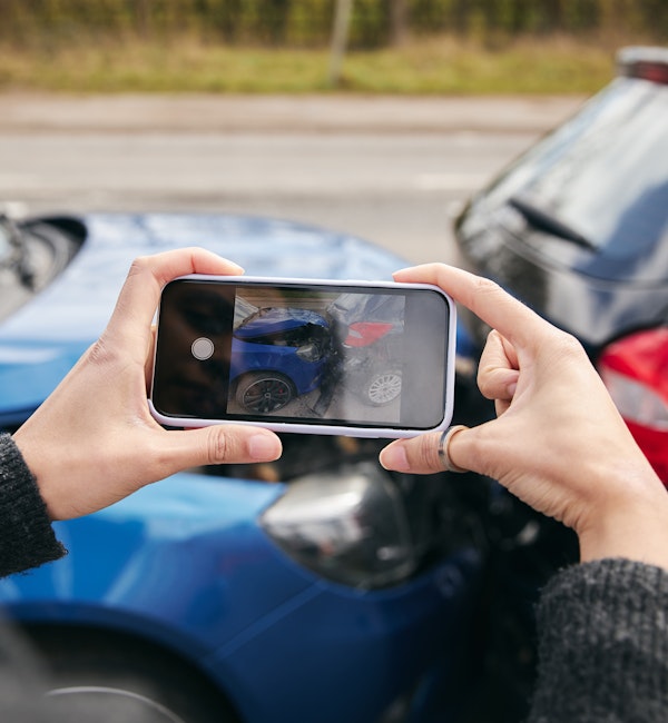 Person taking a photograph of a car wreck