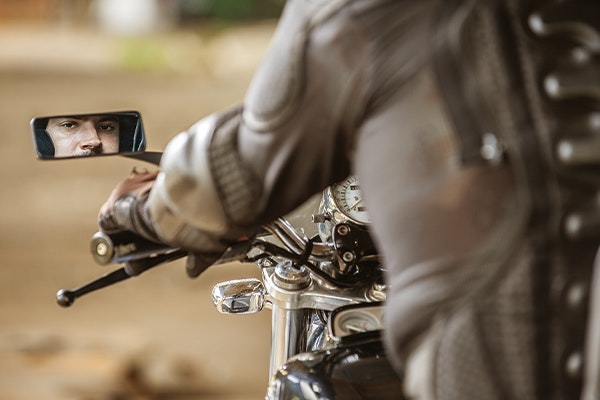 Motorcycle rider looking in rear-view mirror
