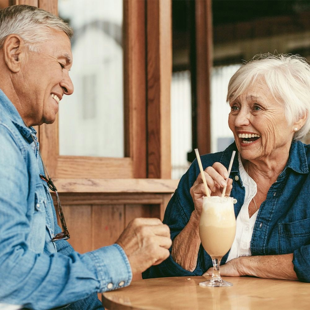 Older couple laughing together over milkshake