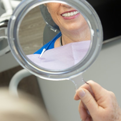 woman looking at her smile in a mirror