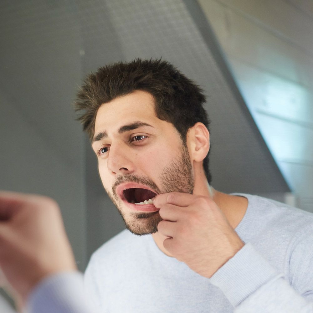 Man inspecting teeth in mirror