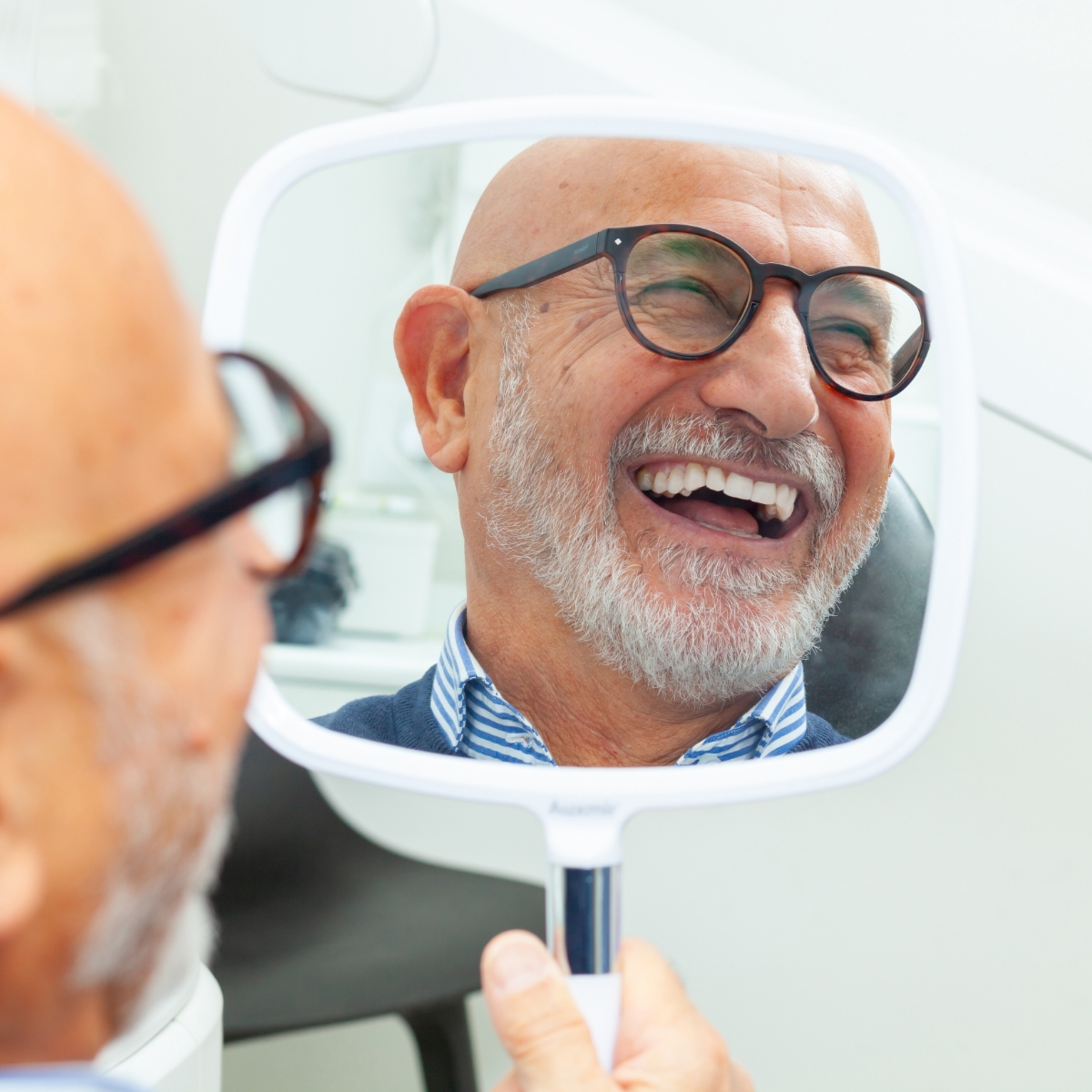 man smiling in mirror at dentists office