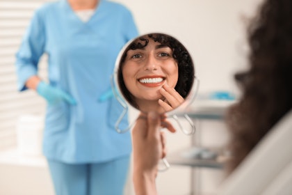 Middle-aged woman smiling in mirror at the dentist