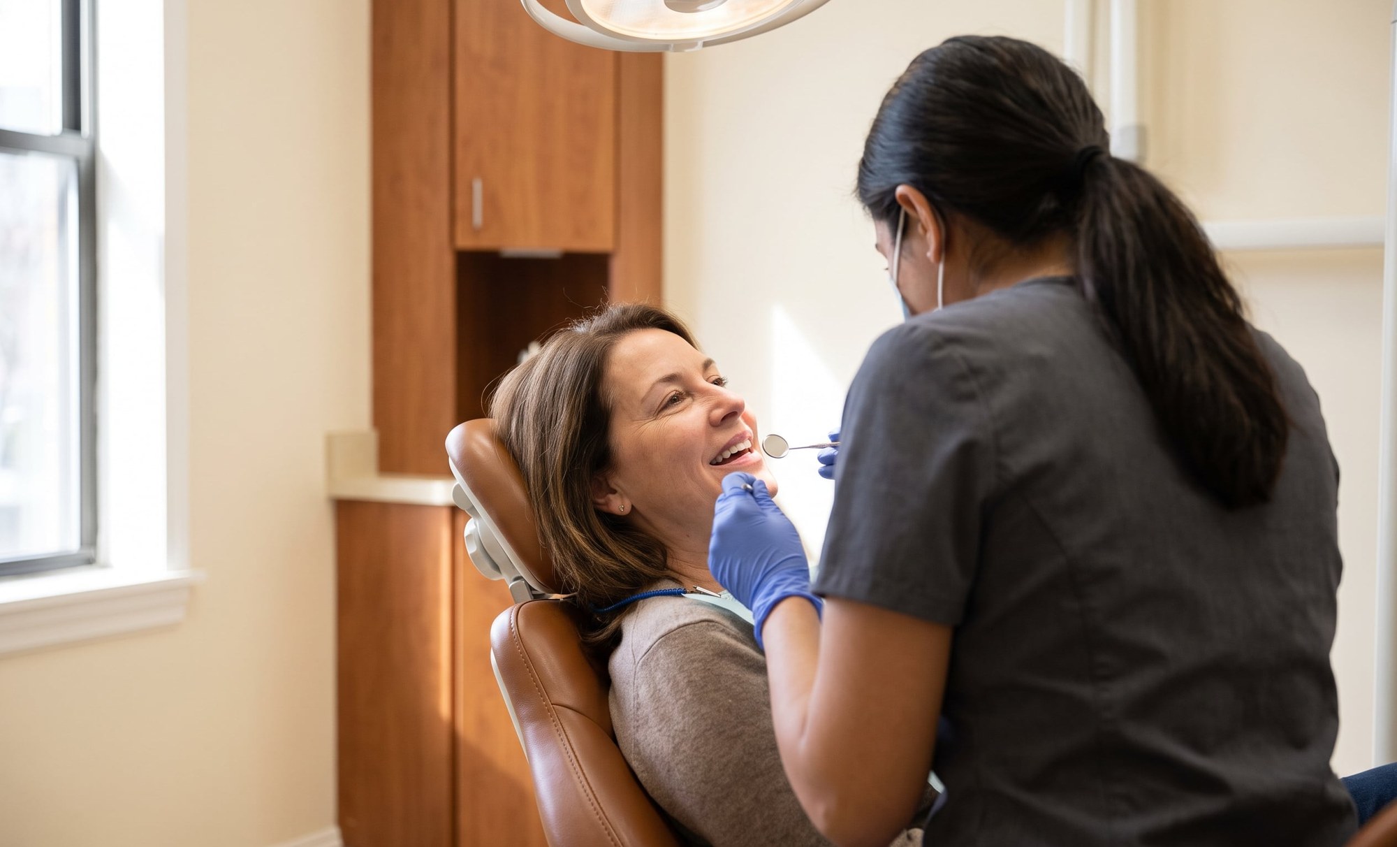 Hygienist checking a smiling patient’s gums during a periodontal exam