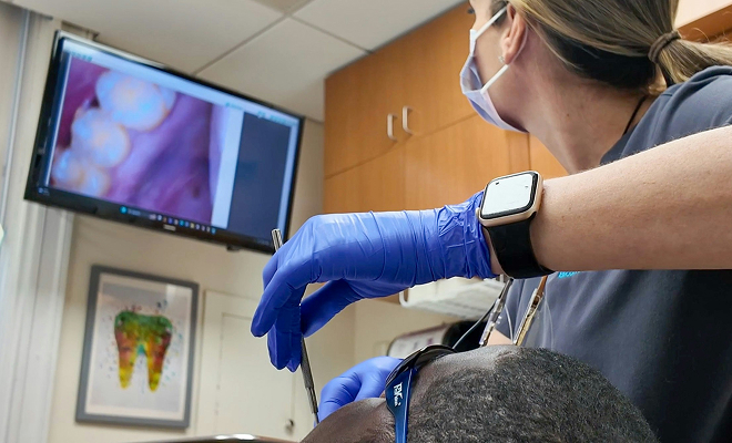 Dentist examining a patient with an intraoral camera shown on the operatory monitor