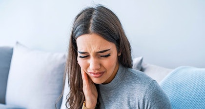 Young woman clutching side of face