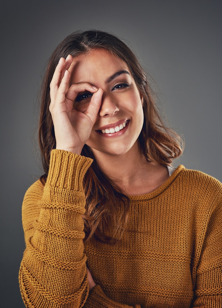 Portrait of a woman framing eye with hand