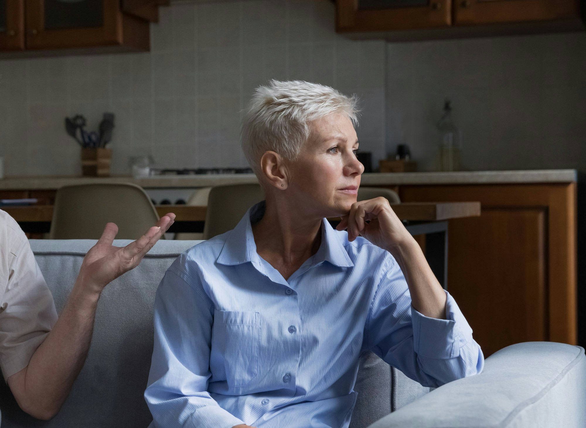 Sad elderly woman turning away from family members abuse