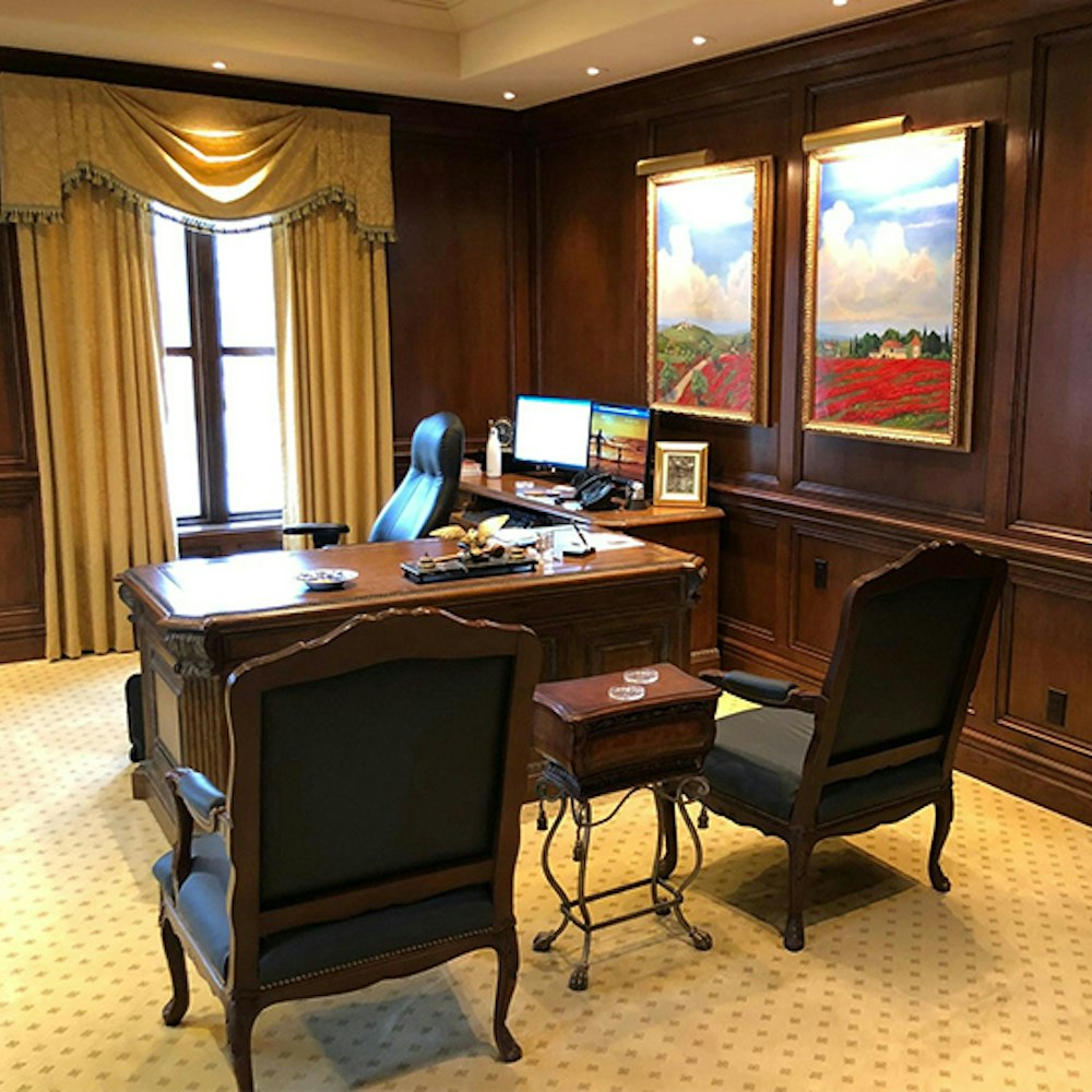 Traditional executive office with wood desk, leather chair, and framed landscape paintings