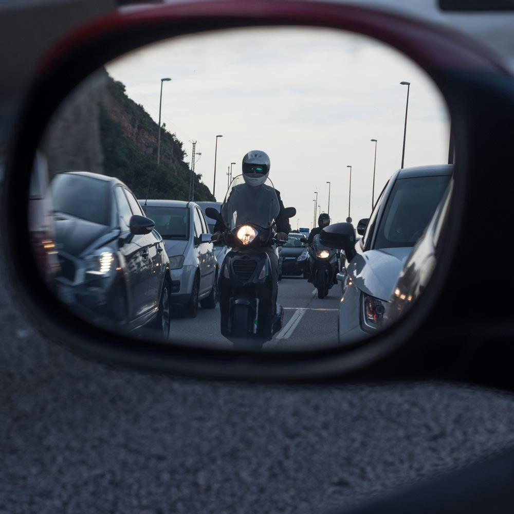 motorcyclist blending into dark cars in a rear view mirror