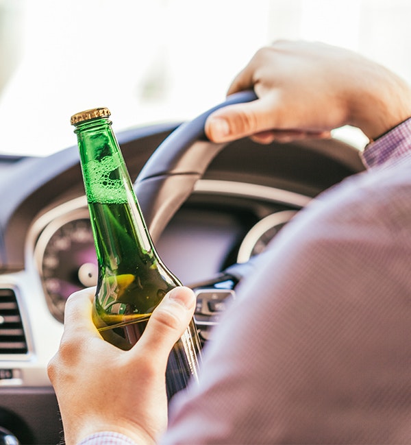 Person reaching for car keys, with alcohol bottle on table