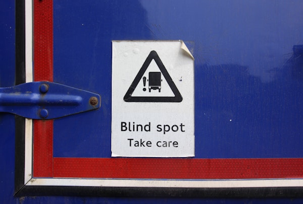 Sign on truck that says, "blind spot take care"