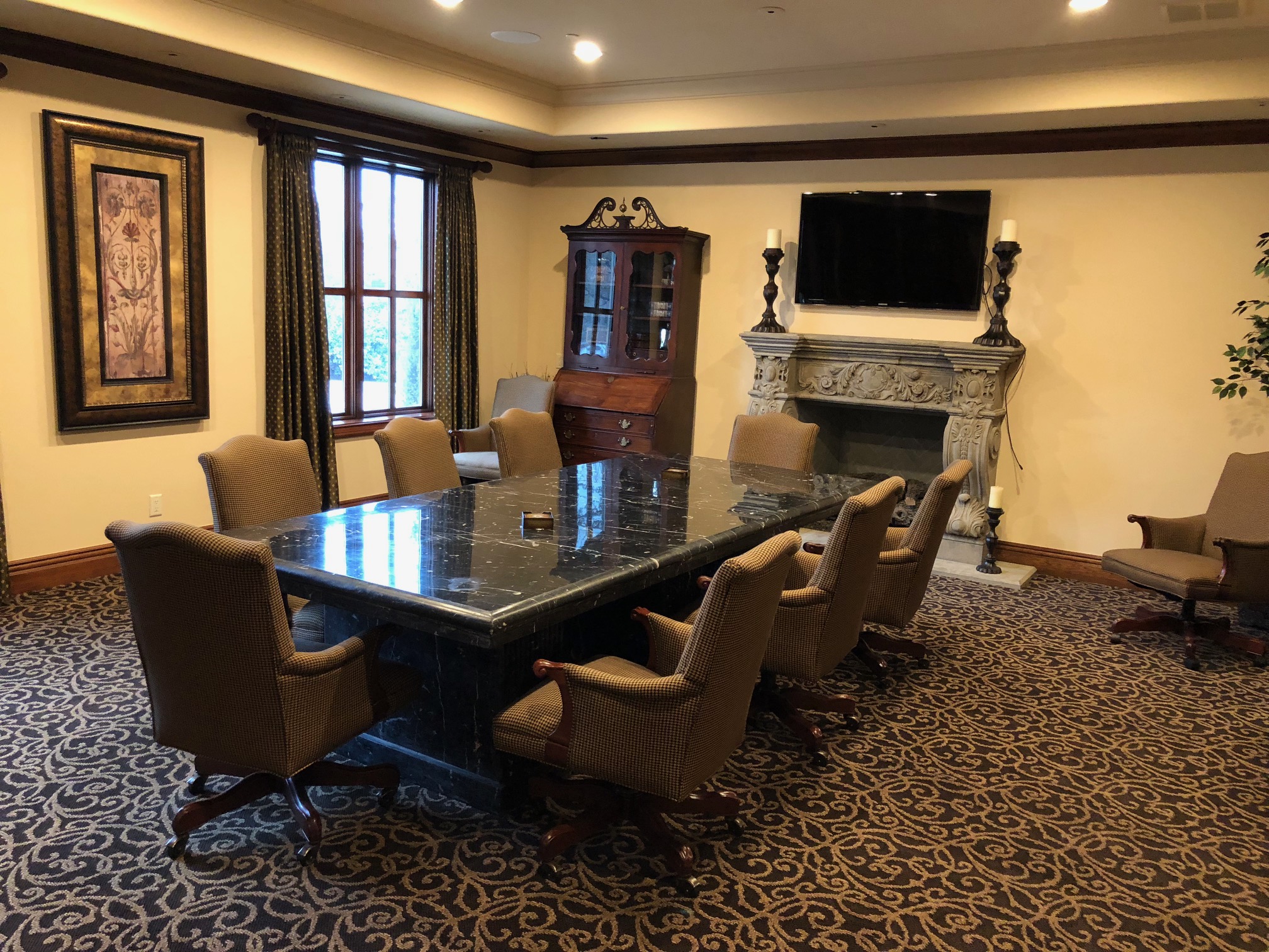 Formal conference room with large marble table, upholstered chairs, and decorative fireplace