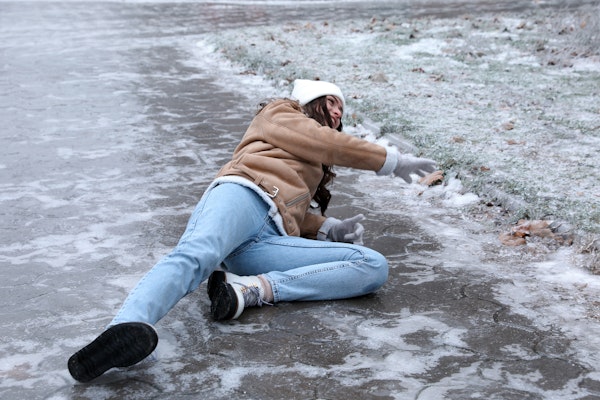 Girl on ground after falling on icy sidewalk