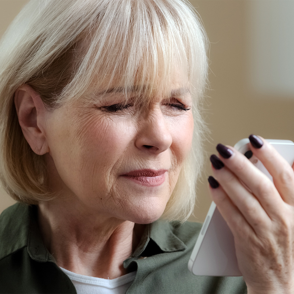 Woman squinting at smartphone screen