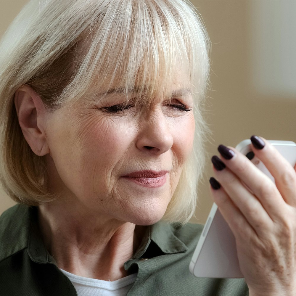 Woman squinting at smartphone screen