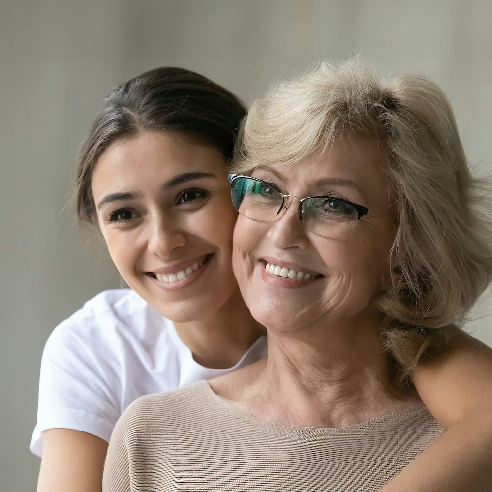 Young woman hugging older woman with All-on-4 implants