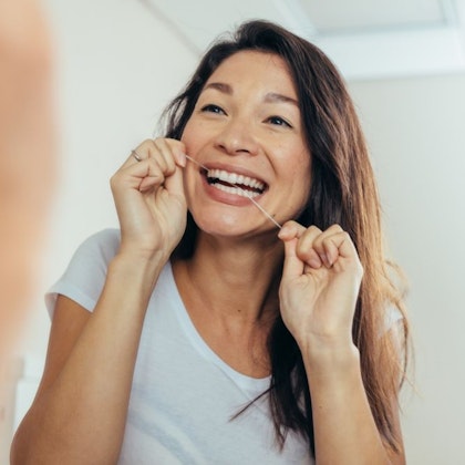 woman flossing in the mirror