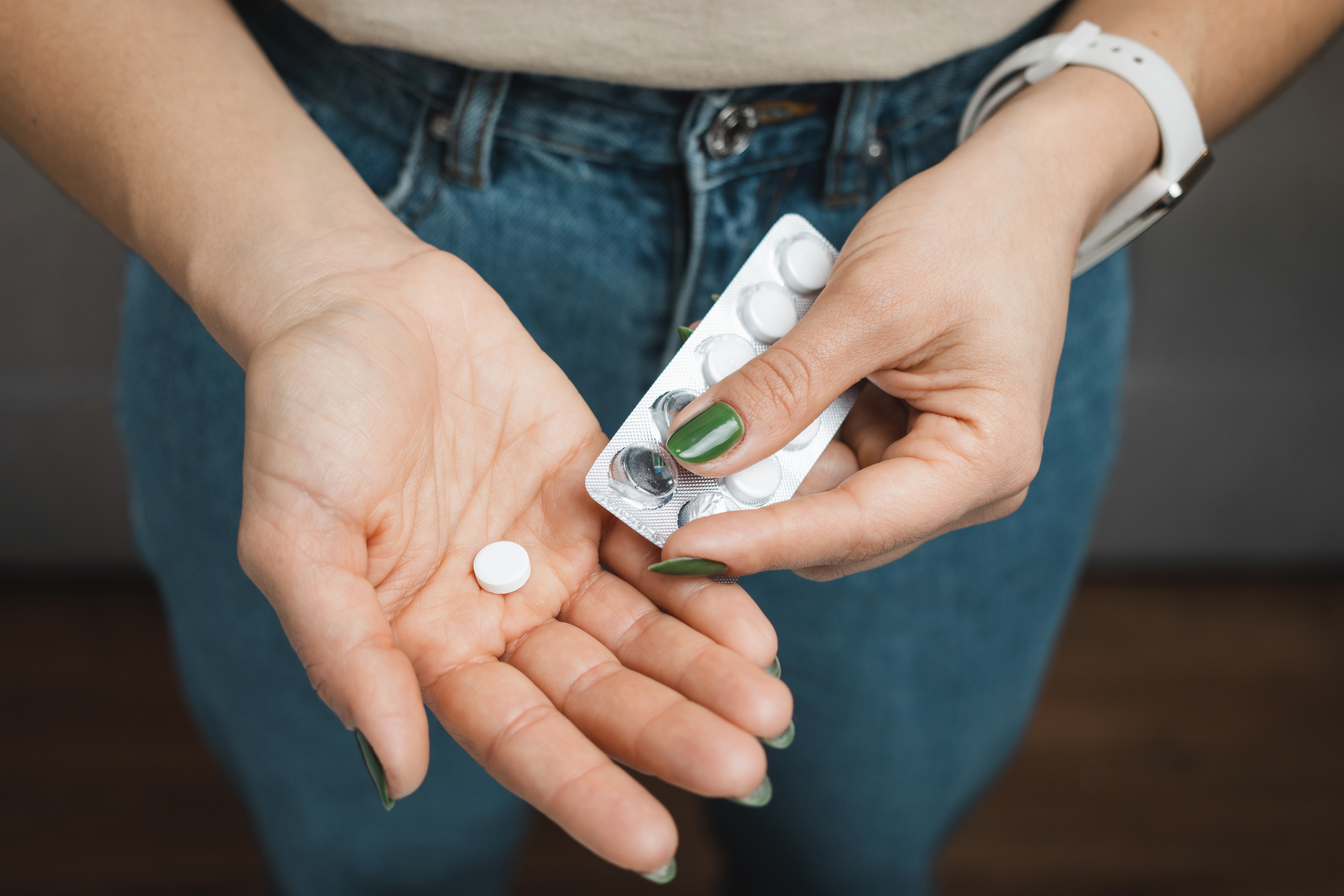 Close up of a woman's hands popping a pill out of a pack
