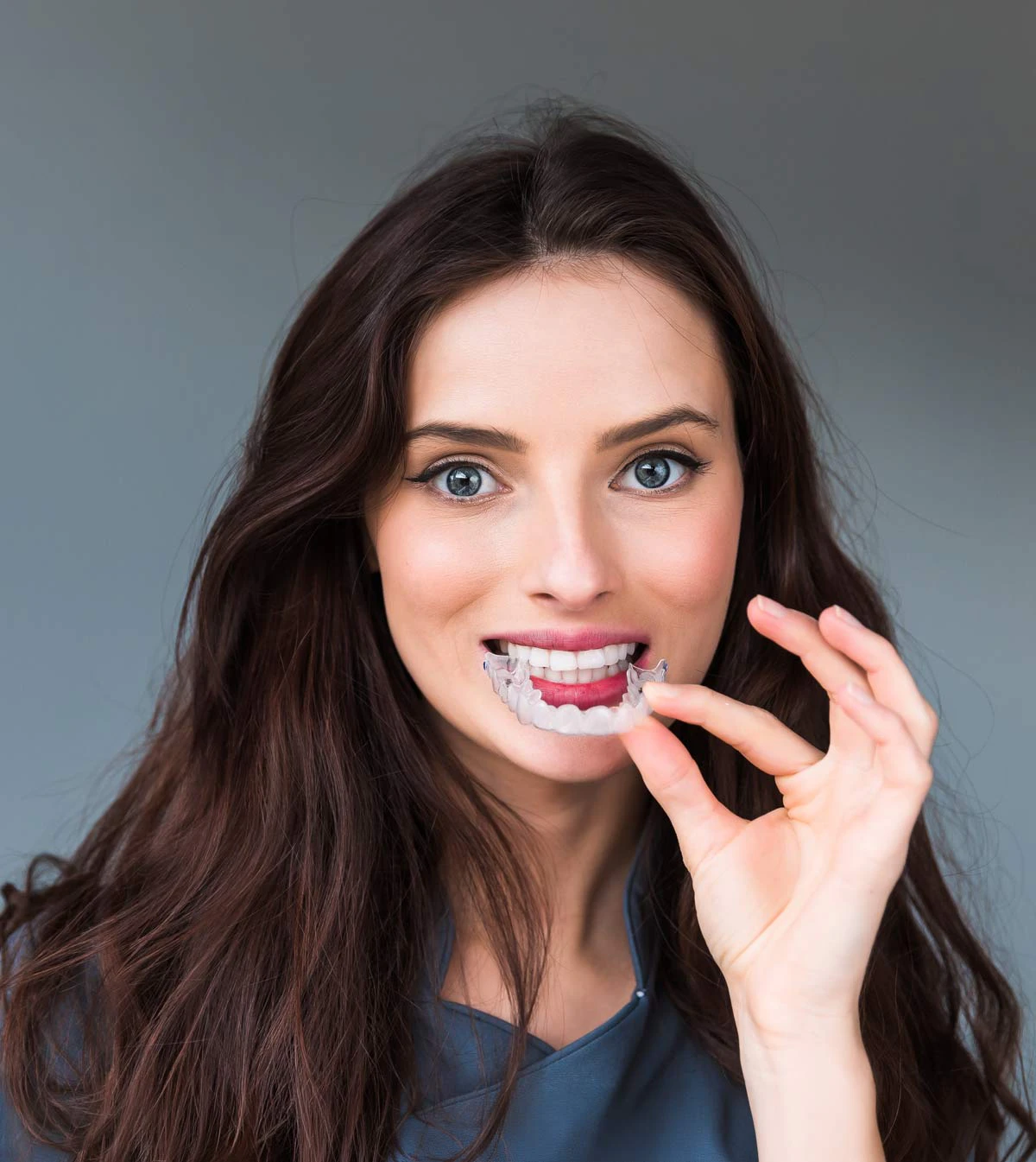 dark haired woman holding an aligner tray