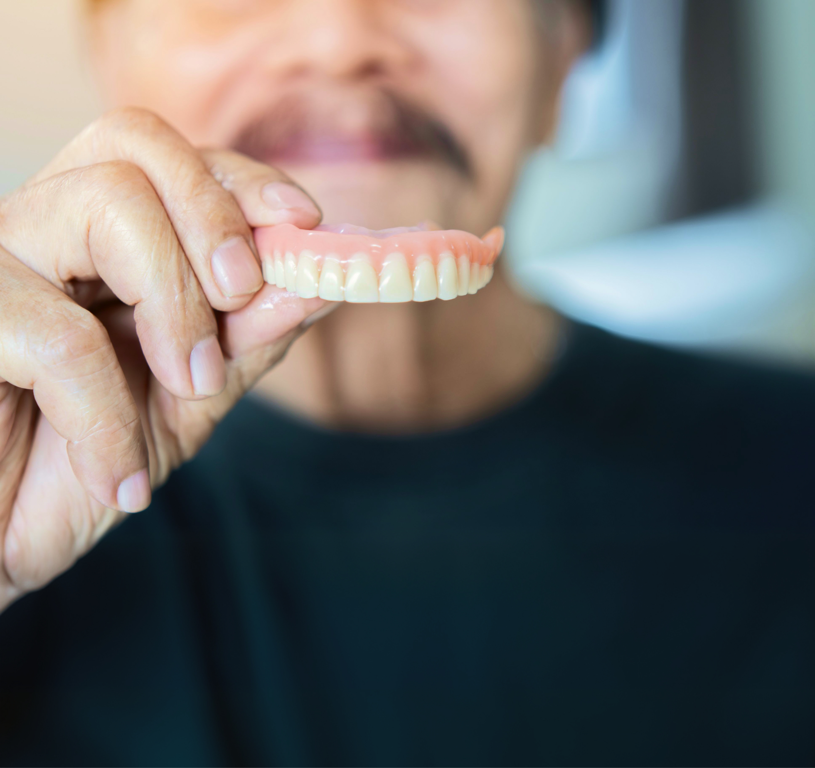man holding up a traditional denture