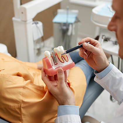 dentist pointing to a model of a dental implant