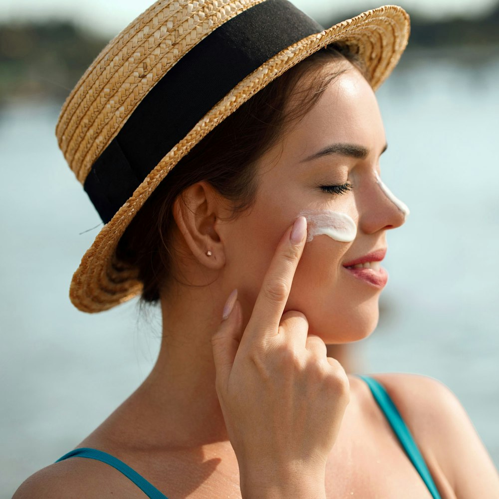 woman in straw hat applying sunscreen