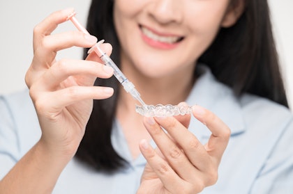 Woman filling teeth whitening tray