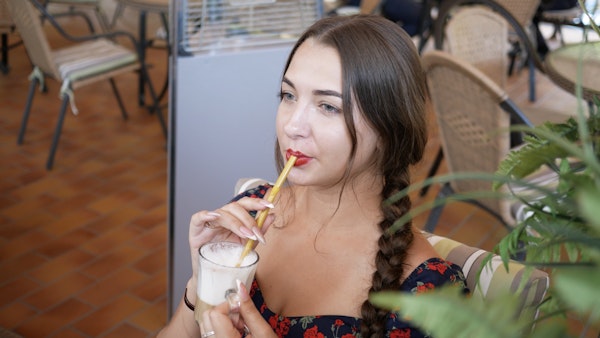 Young woman drinking coffee through a straw