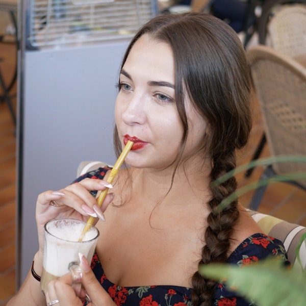 Young woman drinking coffee through a straw