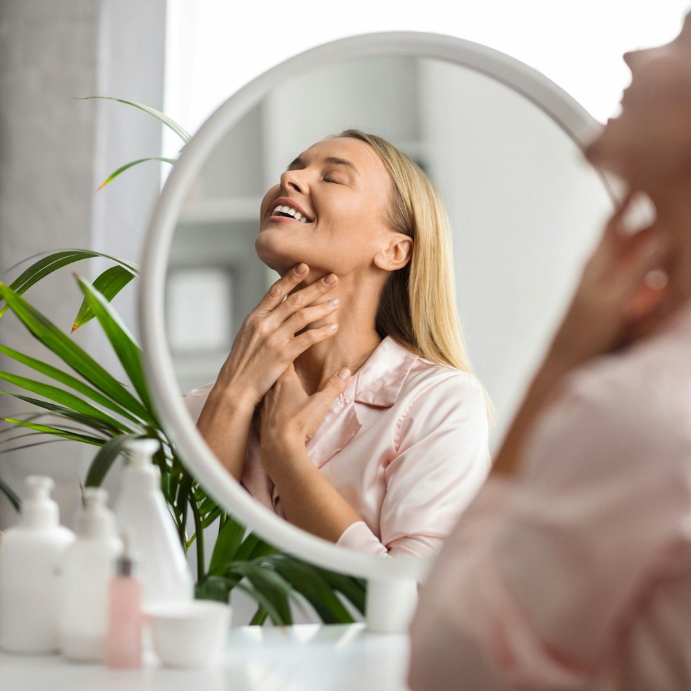 middle-aged woman touching neck while smiling